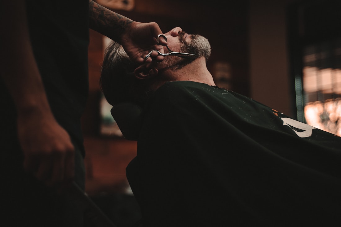 A barber doing precision scissor work in a warm shop