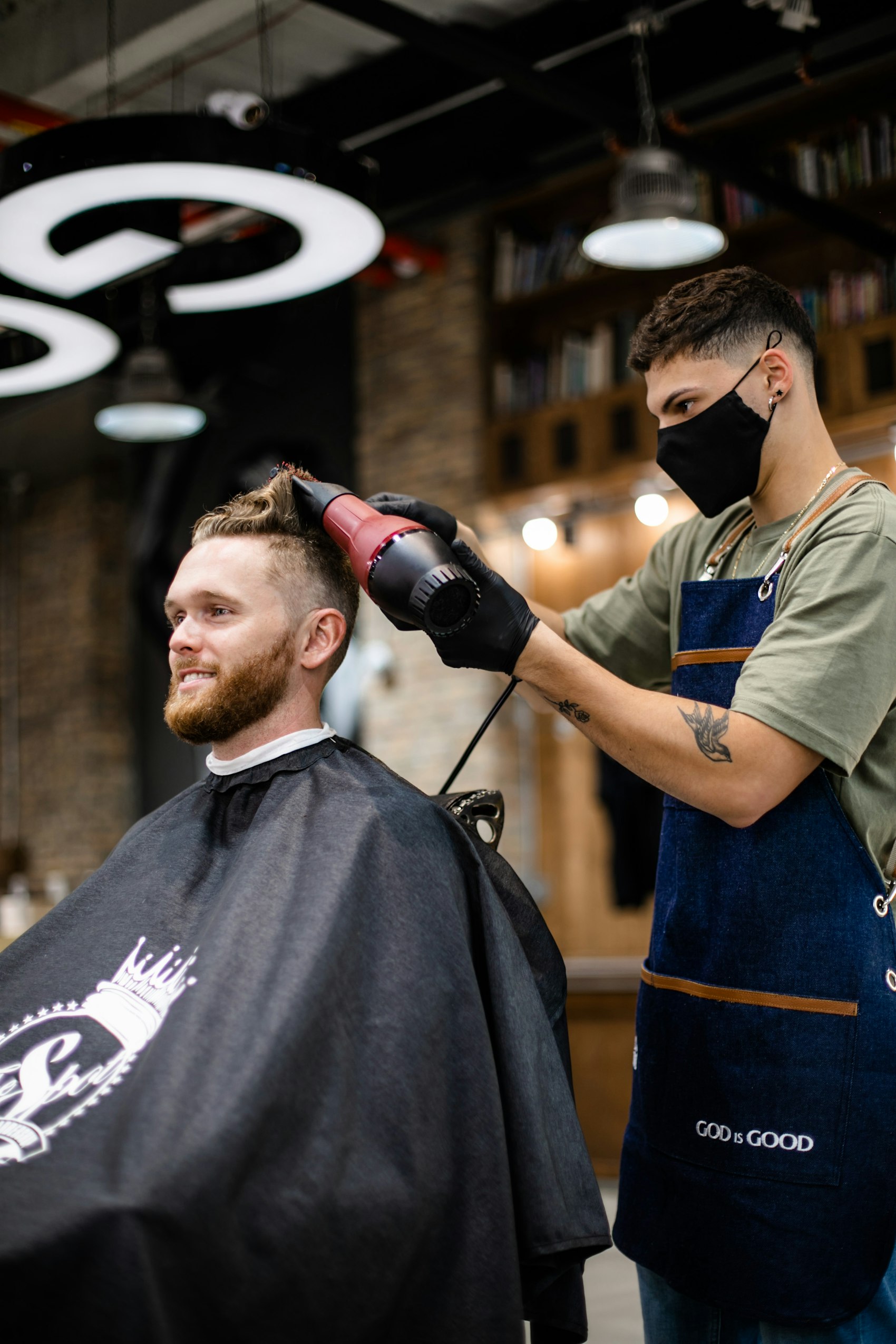 A barber dialing in a fresh cut at the chair inside a warm, low-lit shop